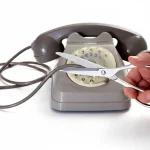 Telefono fisso grigio aziendale con cavo tagliato, simbolo della perdita del numero aziendale